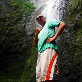 a man standing next to a waterfall