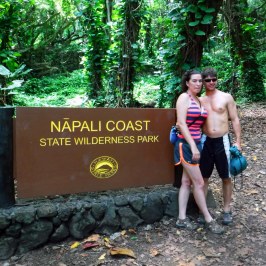 a statue of a man and a woman standing in front of a forest
