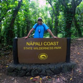 a man holding a sign in front of a forest