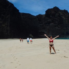 a group of people walking on a beach with a mountain in the background
