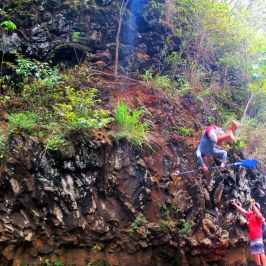 a man riding on the back of a boat next to a river